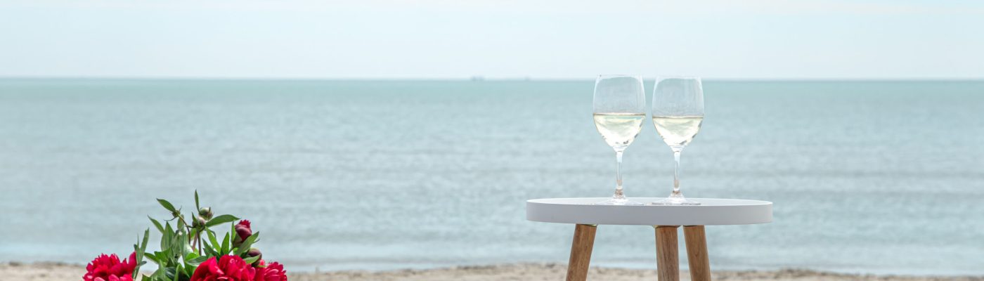 Romantic picnic with flowers and glasses of champagne by the sea. The concept of a holiday.